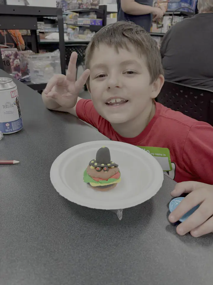 A child shows a clay character made at Izzi's Gym