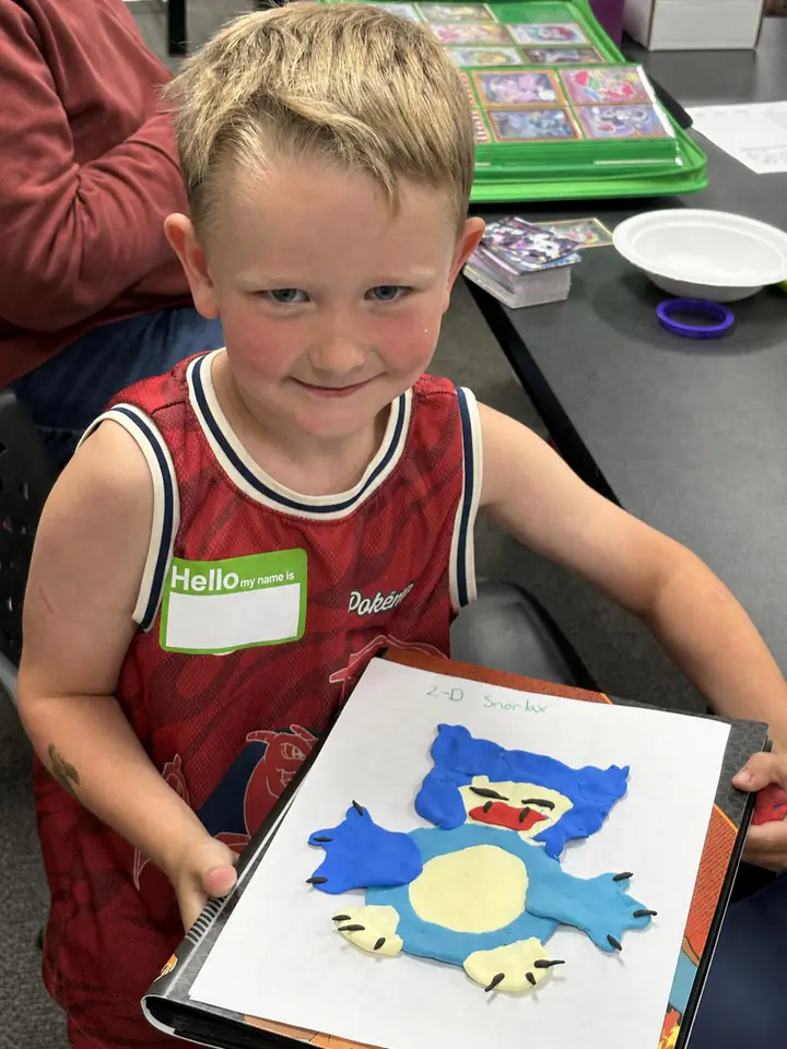 A child holds a handmade Snorlax craft at Izzi's Gym